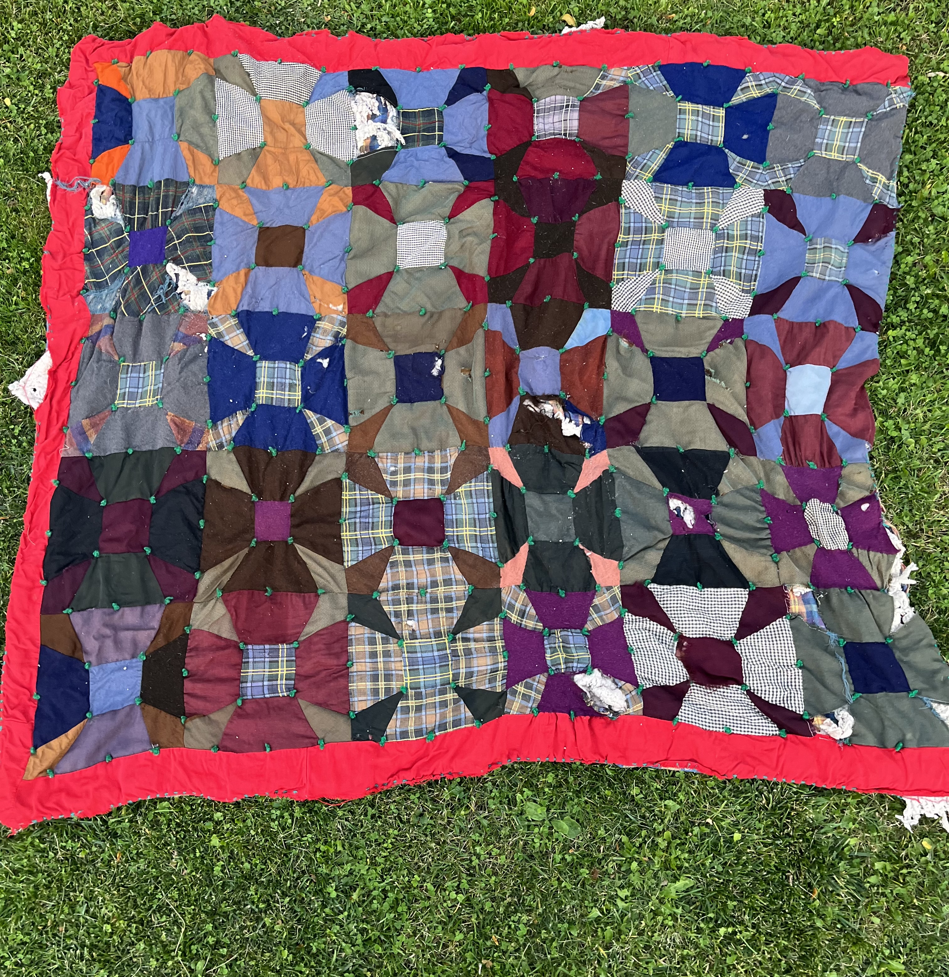 Wool and plaid quilt before restoration — wear and damage visible